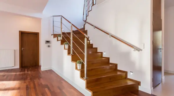 Escaleras de madera sin contrahuella, con barandilla de metal y madera, y luces empotradas. Un diseño moderno y elegante.