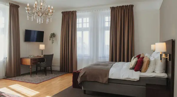 Ett elegant hotellrum på hotel Drott Karlstad med en stor säng, skrivbord och kristallkrona.