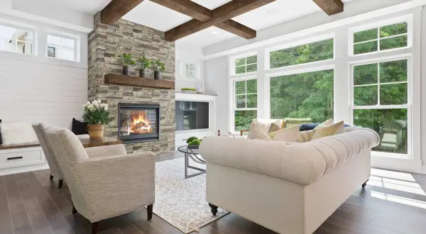Cozy living room with a stone fireplace, tufted sofa, and an accent ceiling with exposed wooden beams.