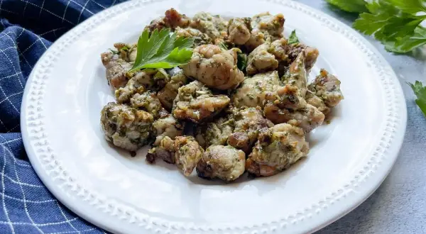 Deliciosas mollejas al ajillo, doradas y jugosas, servidas en un plato blanco con perejil fresco.