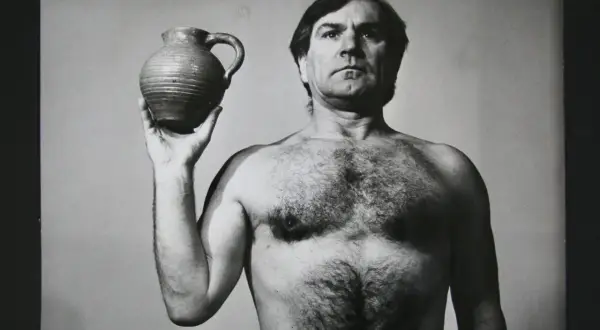 Józef Robakowski, nagi mężczyzna z krzaczastą klatką piersiową, trzyma w dłoni gliniany dzban.