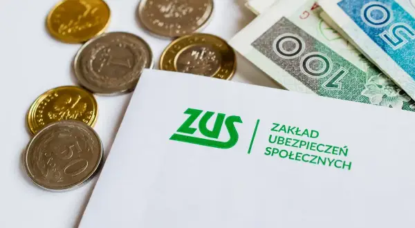 ZUS i pieniądze: ile można dorobić do renty socjalnej? Monety i banknoty leżą obok dokumentu ZUS.