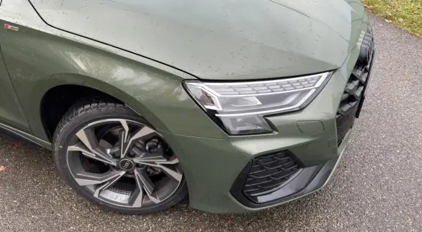 Zielony Audi A3 kombi z felgami S line na mokrej drodze.