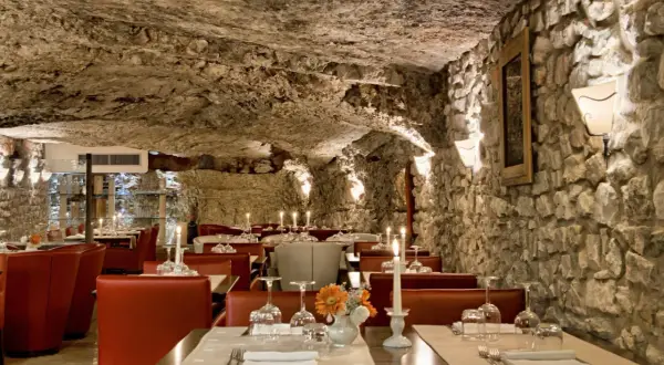 Atmosfera suggestiva in una grotta, ideale per scoprire i migliori ristoranti a Vieste. Tavoli apparecchiati con candele e fiori.