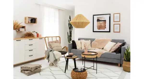 Przytulny salon w stylu rustykalnym z szarą kanapą, wiklinowym fotelem i dekoracjami z naturalnych materiałów.