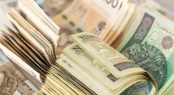 Stosy polskich banknotów 100 zł i 200 zł. Zastanawiasz się, czy wypłacać pieniądze z banku?