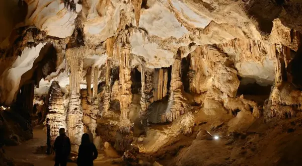 Odkrywanie najpiękniejszych jaskiń w Polsce. Dwie osoby podziwiają imponujące stalaktyty i stalagmity w oświetlonej grocie.