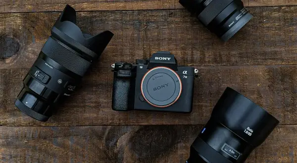 Aparat Sony Alpha 7 III z obiektywami na drewnianym tle.