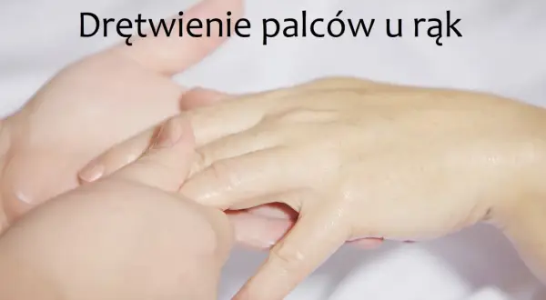Dłoń masowana w okolicy palców, z widocznym napisem "Drętwienie palców u rąk".