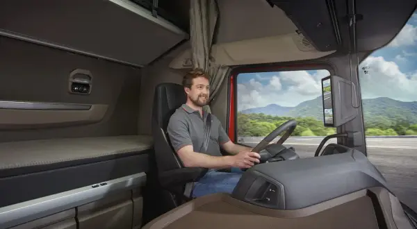L'intérieur d'un camion DAF XG, avec un chauffeur souriant au volant, prêt pour un long voyage.