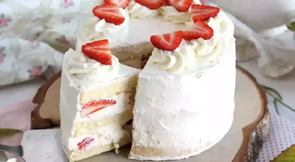 En vacker italiensk tårta med mascarpone, fylld med jordgubbar och täckt med fluffig grädde och färska jordgubbsbitar.