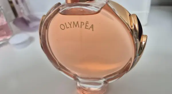 Olympea Paco Rabanne 80ml, w różowym odcieniu, otoczona złotymi zdobieniami.