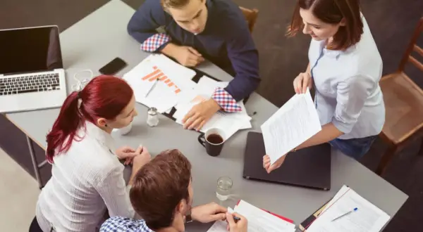 Vier Personen besprechen Dokumente und Diagramme. Sie zeigen **soziale Intelligenz** im Austausch von Ideen und im gemeinsamen Arbeiten.
