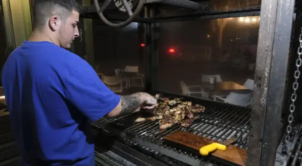 Joven cocinero prepara carnes a la parrilla en un restaurante, quizás en los charros cabo de gata.