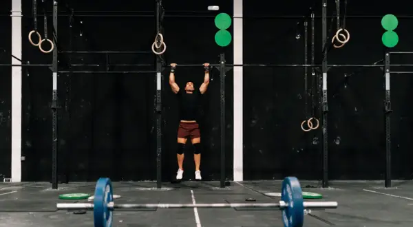Mężczyzna wykonujący podciąganie na drążku w siłowni CrossFit.