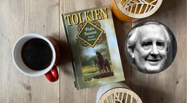 Kawa i książka "Władca Pierścieni" obok portretu J.R.R. Tolkiena. Krótka biografia pisarza inspiruje do podróży w świat fantasy.