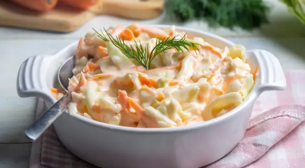 Deliciosa ensalada americana cremosa, con repollo y zanahoria rallados, adornada con eneldo fresco.