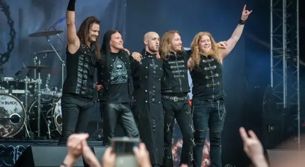 Zespół Beast in Black na koncercie, pięciu muzyków pozuje na scenie, pozdrawiając publiczność.