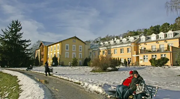 Zimowy krajobraz przed żółtym sanatorium. Zastanawiasz się, ile kosztuje turnus w sanatorium?