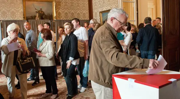 Ludzie w kolejce do głosowania. Dowiedz się, jak głosować za granicą, aby Twój głos miał znaczenie.