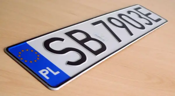 Nowe tablice rejestracyjne z oznaczeniem PL i numerem SB 79035 leżą na drewnianym blacie.
