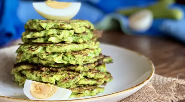 Pila di rosti di zucchine dorati, guarnita con spicchi di uovo sodo. Un piatto leggero e gustoso.