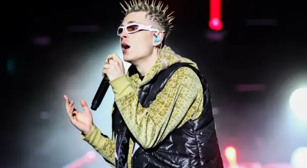 Artysta z kolcami na głowie i białymi okularami śpiewa na scenie. Fani już czekają na oki koncerty 2025!