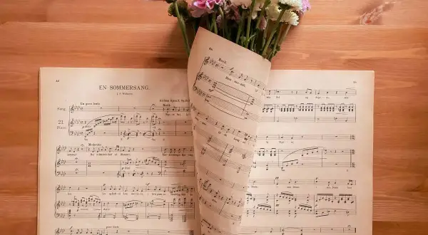 Un mazzo di fiori rosa e bianchi adagiato su spartiti musicali. Le note sembrano le canzoni della mamma, piene di dolcezza.