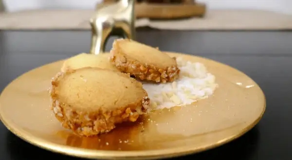 Goldene Platte mit drei Friesenkeksen, bestreut mit Zucker und gehackten Mandeln. Ein goldener Hirsch im Hintergrund. Das ist das original Friesenplätzchen Rezept.