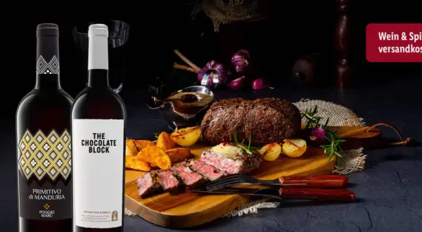 Zwei Flaschen Rotwein neben einem saftigen Wildbraten mit Beilagen. Perfekt, um die Frage zu beantworten: welcher rotwein zum wild kochen.