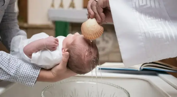 Chrzest dziecka, woda spływa z muszli na główkę. Pytanie, czy chrzestni mogą być tej samej płci, jest tu nieistotne.