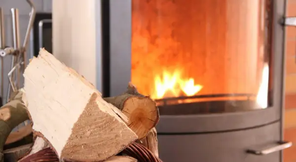 Holzscheite liegen bereit für den Kamin, der gerade nicht benutzt wird. Ein Schornsteinfeger würde sich über die Sauberkeit freuen.