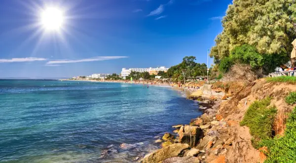 Słoneczna plaża z białymi hotelami w tle. Idealne miejsce na tanie loty we wrześniu, by cieszyć się słońcem i morzem.