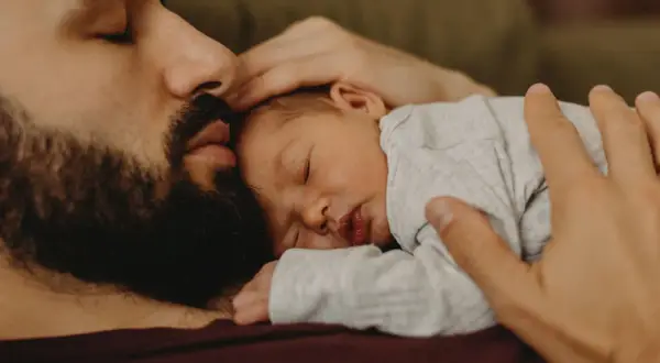 En pappa tröstar sin bebis som gråter hela tiden. Bebisen sover lugnt mot pappans bröst.