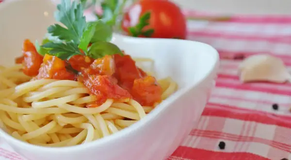 Eine Schüssel mit Spaghetti und einer herzhaften Tomatensoße, garniert mit frischem Basilikum und Petersilie.