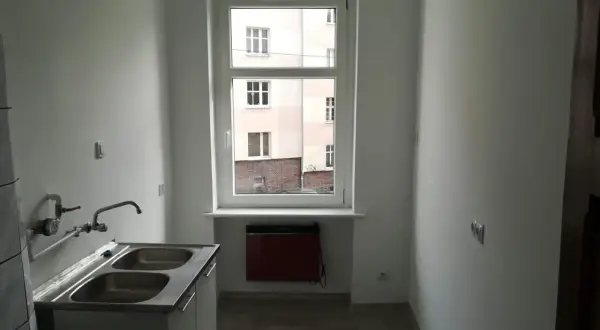 Nowe mieszkanie komunalne, gotowe do zamieszkania. Zastanawiasz się, ile wynosi czynsz za mieszkanie komunalne? Tutaj jest kuchnia z dwukomorowym zlewem i widokiem na podwórko.