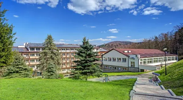 Górnicze sanatorium z panelami słonecznymi na dachu, otoczone zielenią. Miejsce odpoczynku dla każdego górnika.