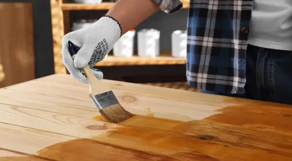 Application d'une première couche de vernis sur un plateau en bois. On se demande combien de couche de vernis bois seront nécessaires pour un fini parfait.