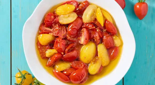 Pomodorini confit in friggitrice ad aria, rossi e gialli, immersi in olio profumato, pronti per insaporire ogni piatto.