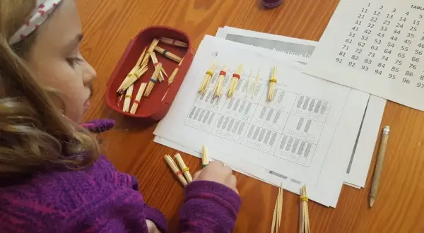 Niña concentrada con pajitas y gomas para resolver operaciones matemáticas, aplicando el método ABN infantil.