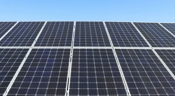 Duża instalacja PV pod błękitnym niebem. Panele słoneczne tworzą równą, ciemną powierzchnię, gotową do produkcji czystej energii.