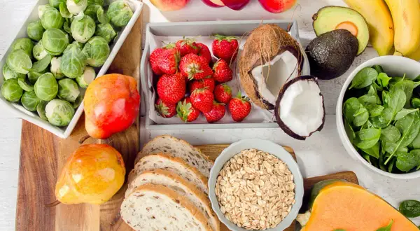 Zdrowe produkty na talerzu: brukselka, truskawki, jabłka, banany, awokado, szpinak, dynia, gruszki, chleb i płatki owsiane. Idealne składniki na dietę 1800 kcal.