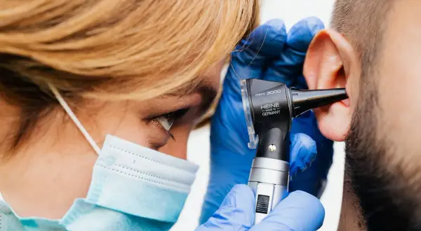 Médico examina oído con otoscopio. Si sufres de dolor de oído, consulta a un profesional para saber qué tomar.