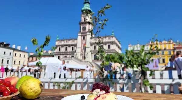 Słodki przysmak na talerzyku, w tle Ratusz i kolorowe kamienice – idealne miejsce na festiwal wina Zamość.