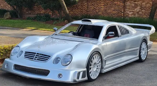 Srebrny Mercedes CLK GTR z masywnym spojlerem i wlotem powietrza na dachu, gotowy do wyścigu.