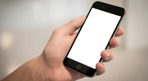 Dłoń trzyma smartfon z pustym ekranem. Chcesz wiedzieć, jak sprawdzić telefon?