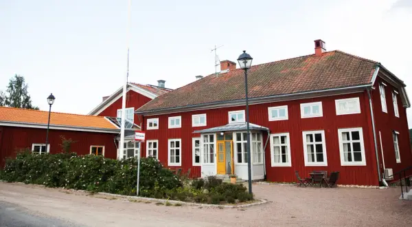 Rött stenhus med orange tak, ett stf vandrarhem med en gul dörr och en flaggstång.