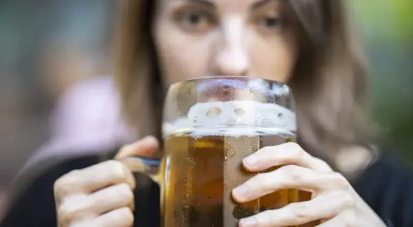 Kobieta pije piwo z dużego kufla. Czy zastanawiasz się nad piwo kcal?