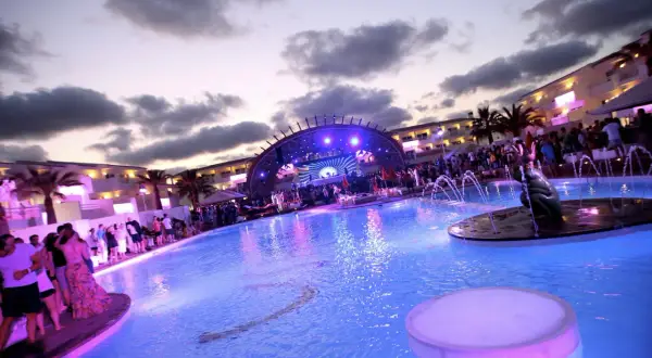 Festa in piscina a Ibiza con DJ set e folla festante. Un'atmosfera vibrante per gli eventi di Ibiza a settembre.