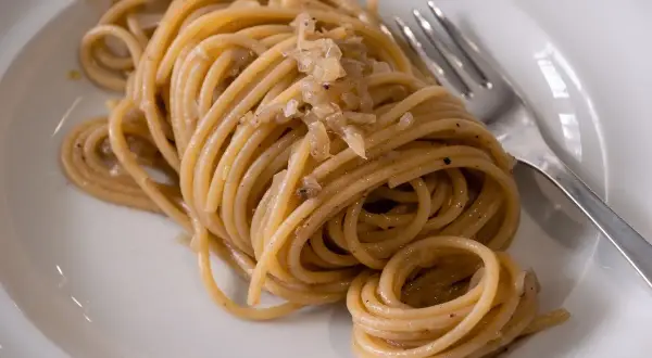 Un piatto di bigoli con le sarde, pasta fresca condita con un sugo saporito.